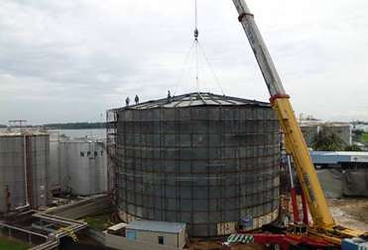 Crane lifting the roof of a large storage tank