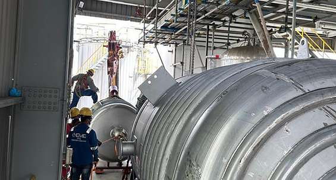 Workers installing a large stainless vessel